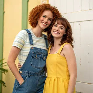 Two friends posing: one tall with curly red hair in denim ov