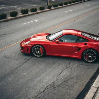 A bright red sports car parked on a gray asphalt road — the 