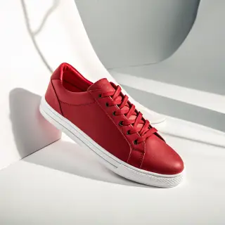 A single red sneaker on a clean white background with soft s