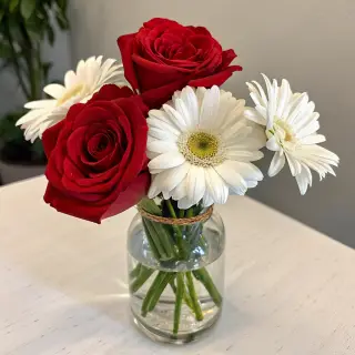 4 red roses and 2 white daisies in a glass vase on a table