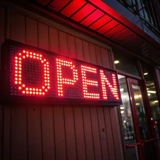 The word 'OPEN' displayed on a red LED sign with glowing pix