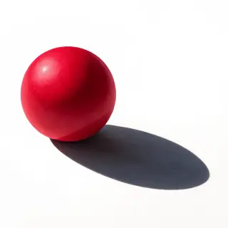 A red sphere on a white surface with a single shadow cast to