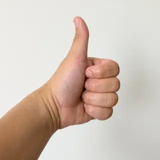 A hand giving a thumbs-up with four fingers curled and thumb