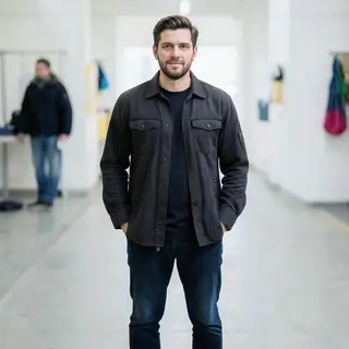 A man standing straight facing the camera, hands in pockets,