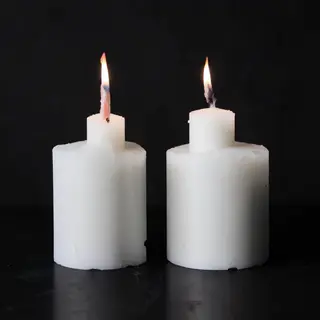 Exactly 4 white candles standing on a dark surface
