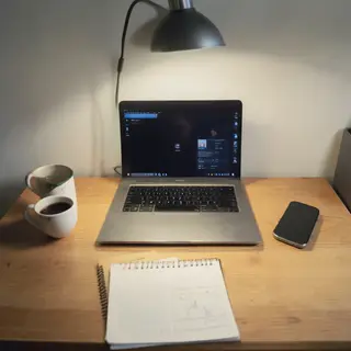 A desk scene: laptop in the center, coffee mug to the left, 