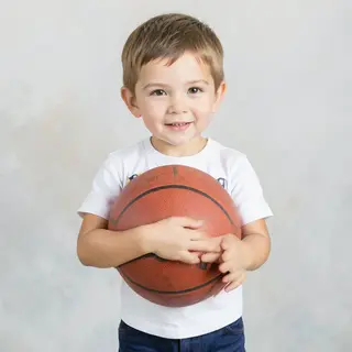 A child holding a basketball, both at correct relative sizes