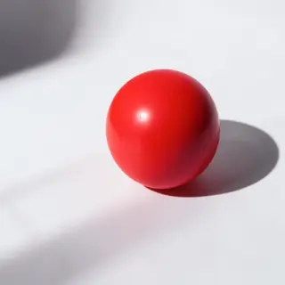 A red sphere on a white surface with a single shadow cast to