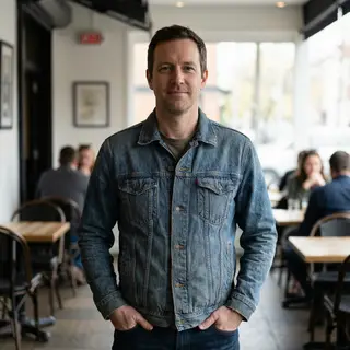 A man standing straight facing the camera, hands in pockets,