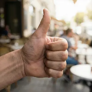 A hand giving a thumbs-up with four fingers curled and thumb