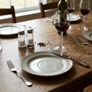 A dinner table scene with a plate, fork, knife, wine glass, 