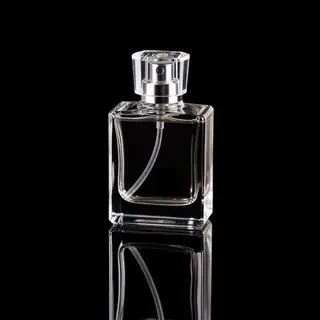A clear glass perfume bottle on a reflective black surface w