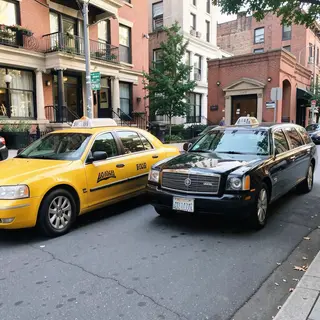 A yellow taxi and a black limousine parked next to each othe
