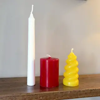 A tall thin white candle, a short fat red candle, and a medi