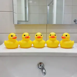 Exactly 5 yellow rubber ducks sitting in a row on a bathroom