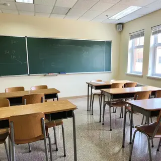 A classroom with desks and a chalkboard but no students