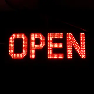 The word 'OPEN' displayed on a red LED sign with glowing pix