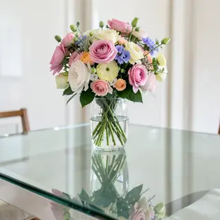 A vase of flowers on a glass table with a clear reflection v