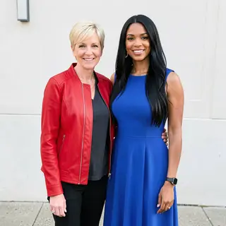 Two women standing side by side: one with short blonde hair 