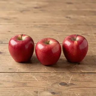 Exactly 3 red apples arranged on a wooden table