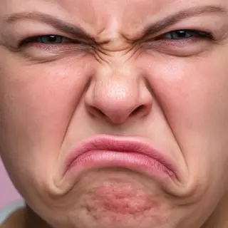A close-up of a person's face showing clear disgust, nose wr