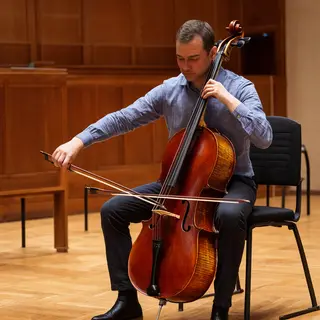 A cellist seated with correct posture, legs around the instr