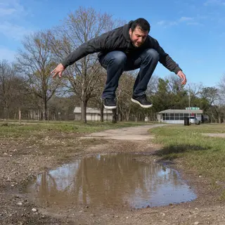 A man captured mid-jump over a puddle, body in the air with 