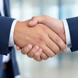 Two people shaking hands in a professional setting, all fing