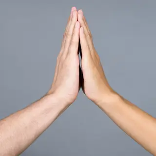 Two people doing a high-five, palms meeting with all fingers