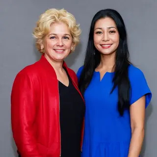 Two women standing side by side: one with short blonde hair 