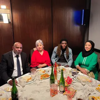 Four people at a dinner table: a bald man in a suit, a woman