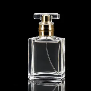 A clear glass perfume bottle on a reflective black surface w