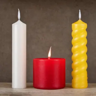A tall thin white candle, a short fat red candle, and a medi