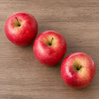 Exactly 3 red apples arranged on a wooden table
