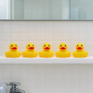 Exactly 5 yellow rubber ducks sitting in a row on a bathroom