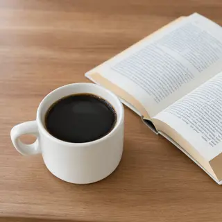 A coffee mug next to an open book on a desk