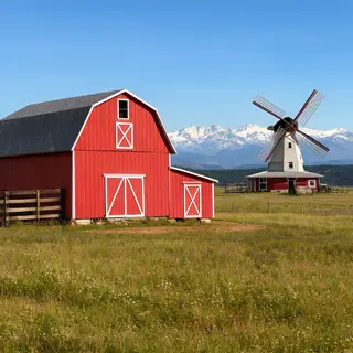 A landscape with a red barn in the foreground at large scale