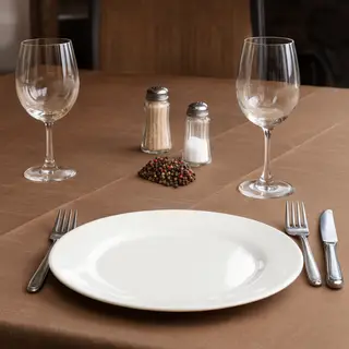 A dinner table scene with a plate, fork, knife, wine glass, 