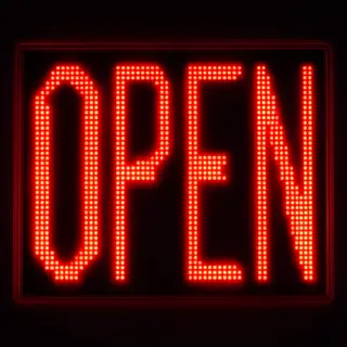 The word 'OPEN' displayed on a red LED sign with glowing pix