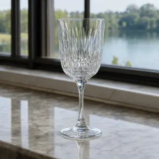 A crystal wine glass on a polished marble counter next to a 