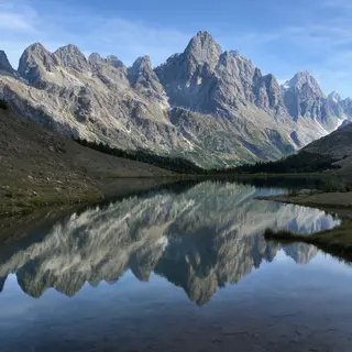 A mountain range reflected in a still alpine lake, with the 