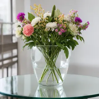 A vase of flowers on a glass table with a clear reflection v