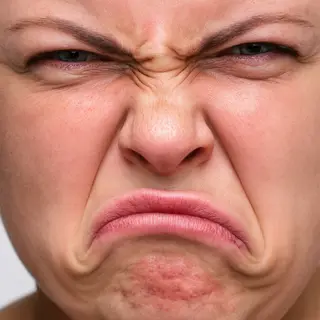 A close-up of a person's face showing clear disgust, nose wr