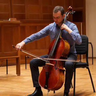 A cellist seated with correct posture, legs around the instr