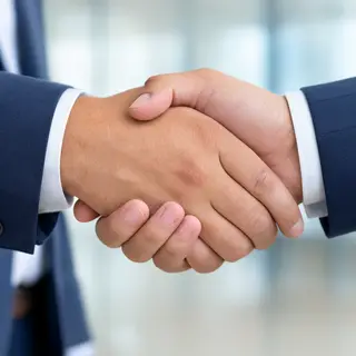 Two people shaking hands in a professional setting, all fing