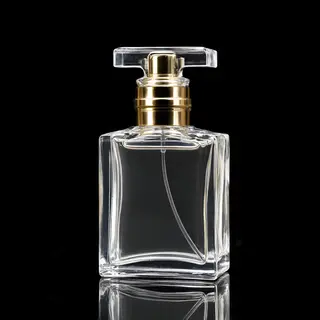 A clear glass perfume bottle on a reflective black surface w