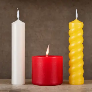 A tall thin white candle, a short fat red candle, and a medi