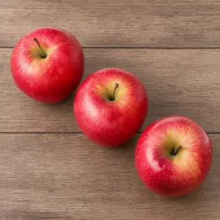 Exactly 3 red apples arranged on a wooden table