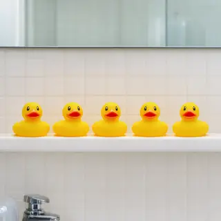 Exactly 5 yellow rubber ducks sitting in a row on a bathroom