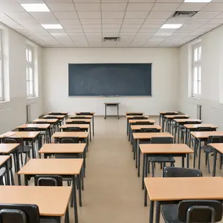 A classroom with desks and a chalkboard but no students